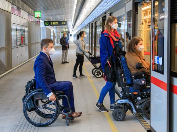 ein Rollstuhlnutzer nähert sich einen U-Bahn-Zug die Tür ist offen man sieht die Klapprampe