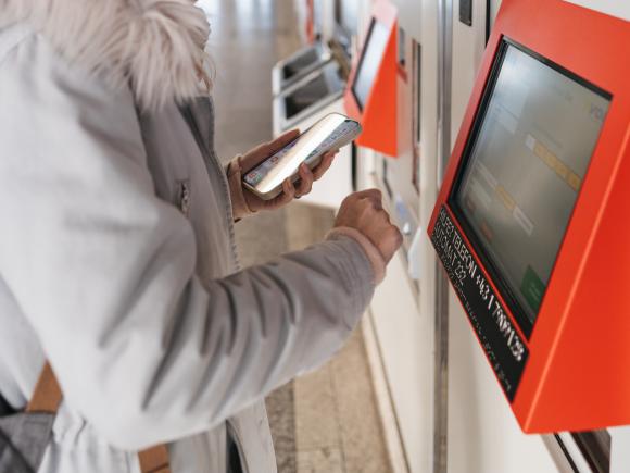 Blonde Dame mit Winterjacke kauft ein Ticket bei einem Fahrscheinautomat der Wiener Linien